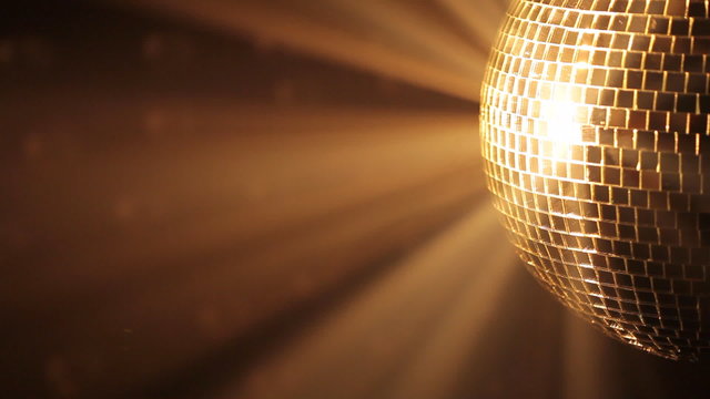 Shiny disco ball with golden reflection and rays in haze