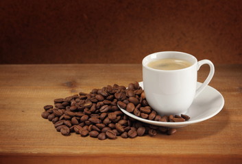 Coffee beans, cup and sauсer on a wooden table