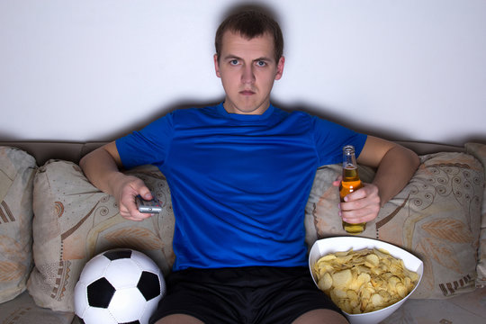 football supporter in uniform sitting in living room and watchin