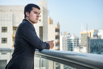 man looking on city standing at the balcony