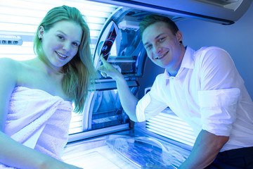 Employee in a solarium counseling customer at tanning bed