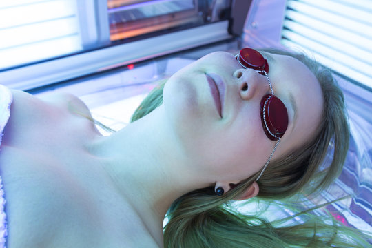 Woman with sunglasses on tanning bed in solarium