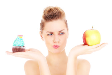 Woman trying to make a decision between cupcake and apple