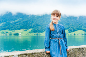 Outdoor portrait of a cute little girl in jeans dress