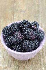 bowl of fresh blackberries on a wooden background close-up