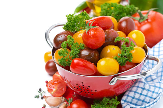 Assorted cherry tomatoes and greens in a colander, isolated