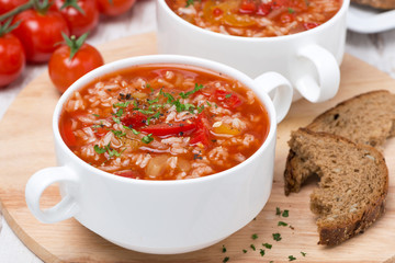 tomato soup with rice, vegetables and herbs on wooden table