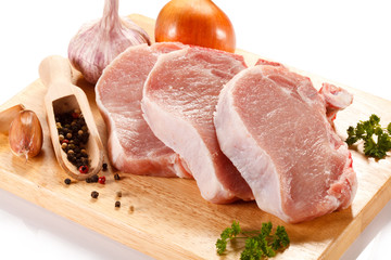 Raw pork on cutting board and vegetables