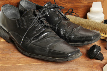 shoe care equipment and formal black shoe on wooden background