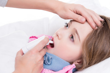 Little girl with sore throat using spray.