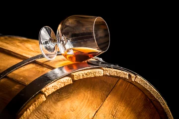 Tuinposter Glass of cognac on the vintage barrel © shaiith
