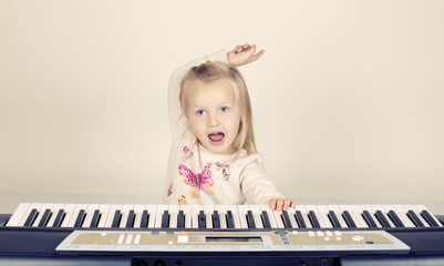 adorable funny little girl playing in synthesizer