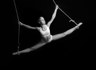 Young woman gymnast. On black background