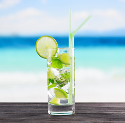 Glass of mojito cocktail on a beach
