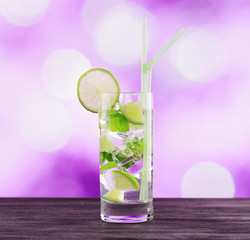 Glass of mojito cocktail on pink background
