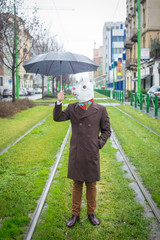Young man wearing rabbit mask standing with umbrella on street