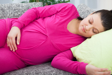 Pregnant woman lying on the sofa and resting