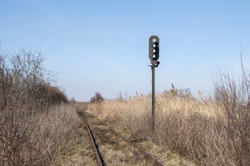 Abandoned rail line and empty railway traffic light in field