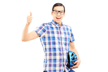 Smiling guy standing holding helmet and giving thumb up