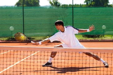 Zelfklevend Fotobehang Young man playing tennis © luckybusiness