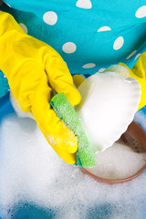 Housewife washing dishes in wash-basin