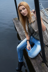 Obraz na płótnie Canvas Fashion beautiful girl on the pier next to the lake