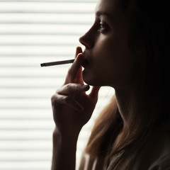 Fototapeta premium Beautiful sexy fashion girl with a cigarette close-up
