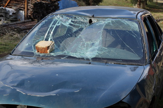 Broken green car with a brick on the windshield