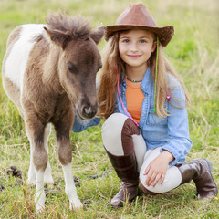 Little foal - cute girl takes care of the pony foal