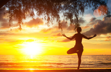 Young woman practicing yoga by the sea beach.