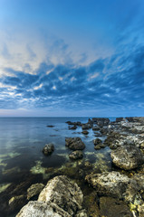 Fototapeta na wymiar The rocky shore of the peaceful ocean at sunset