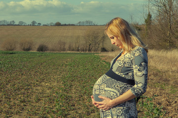 Sad pregnant woman in a field, week 38