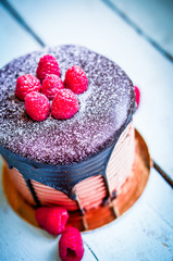 Chocolate cake with raspberries on wooden background