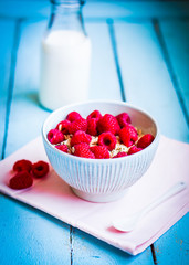 Granola with raspberries in a bowl on wooden background