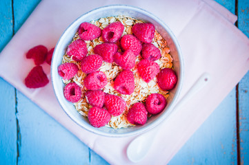 Granola with raspberries in a bowl on wooden background
