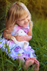 Cute little girl with a bunny rabbit has a easter at green grass