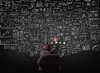 Businessman sitting in front of a blackboard with charts
