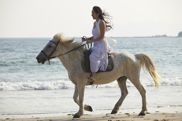 a woman riding horse on beach