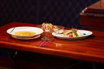 Image of baked fish with vegetables, soup and dessert on table