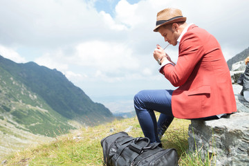 young man lights cigarette in mountains