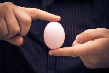 White hen egg held fingers