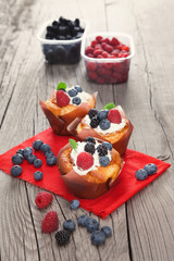 Cupcakes with berries on wooden table