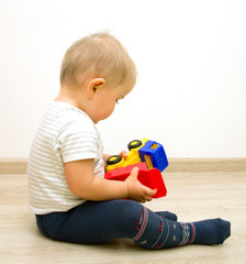 Lonely little boy   playing with plastic toy truck on a floor - 61836856