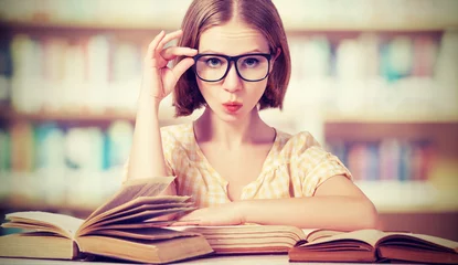 Poster funny girl student with glasses reading books © JenkoAtaman