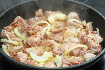 Fried meat with onion in a frying pan