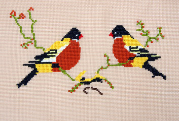 embroidery by cross-stitch pattern birds on yellow fabric