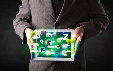 Young person showing tablet with abstract letters and sky