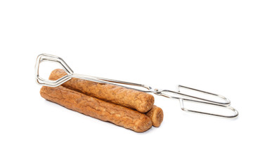 Three frikandellen with frying tongs