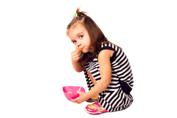 Obraz na płótnie Canvas Small girl eat corn flakes isolated on white