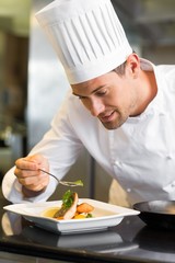 Smiling male chef garnishing food in kitchen